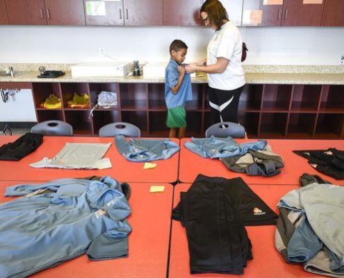 Athlos student tries on uniform