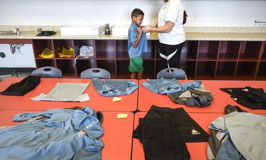 Athlos student tries on uniform