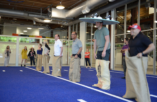 Employees participate in a potato sack race on the indoor turf